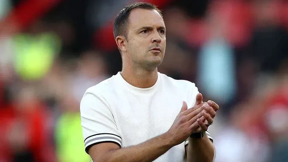 Entrenador aplaudiendo en el banquillo durante el partido