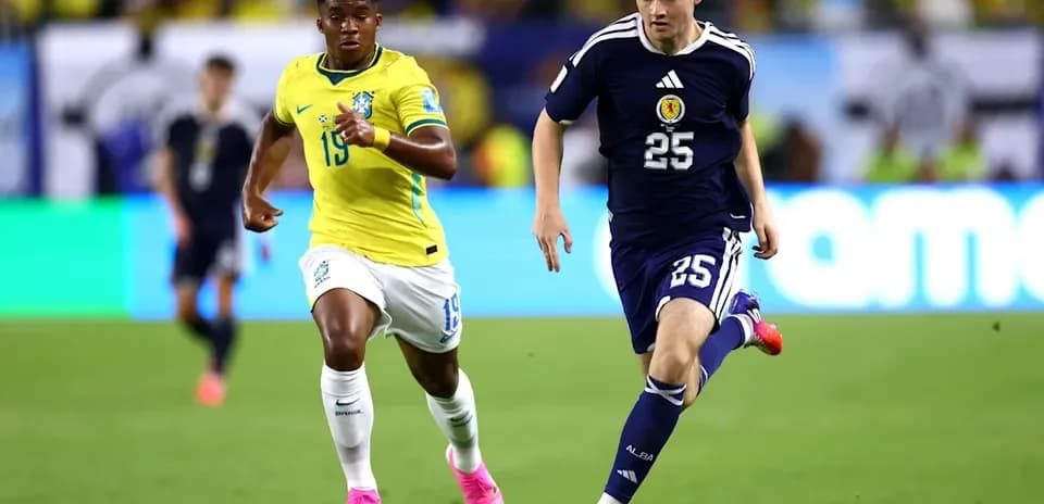 Jugador de Japón corriendo con balón, Brasil persiguiéndolo