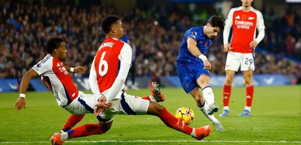 Jugador de Chelsea disparando mientras dos defensores de Arsenal intentan detenerlo
