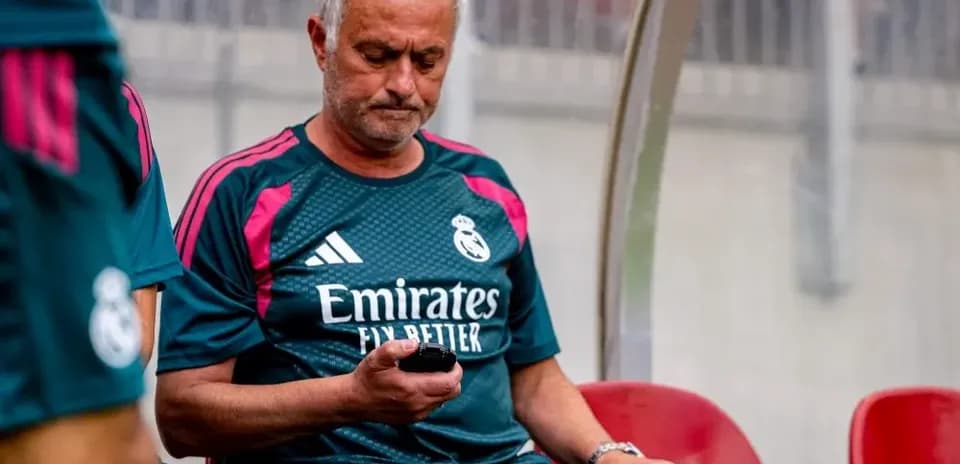 Entrenador de Real Madrid revisando su teléfono en banco