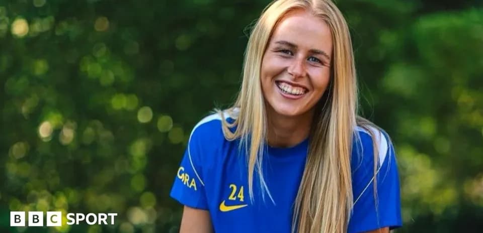 Jugadora de fútbol sonriendo en camiseta azul