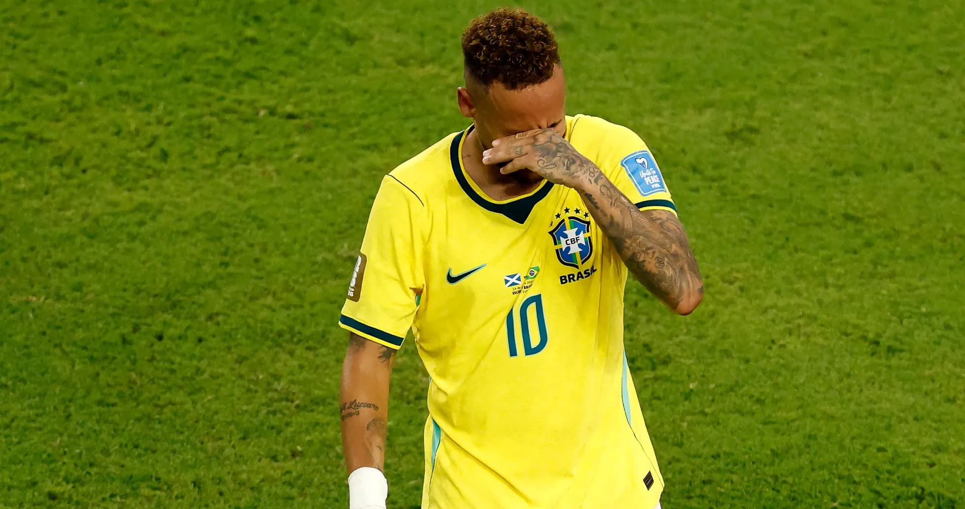 Jugador de Brasil se cubre la cara en el campo