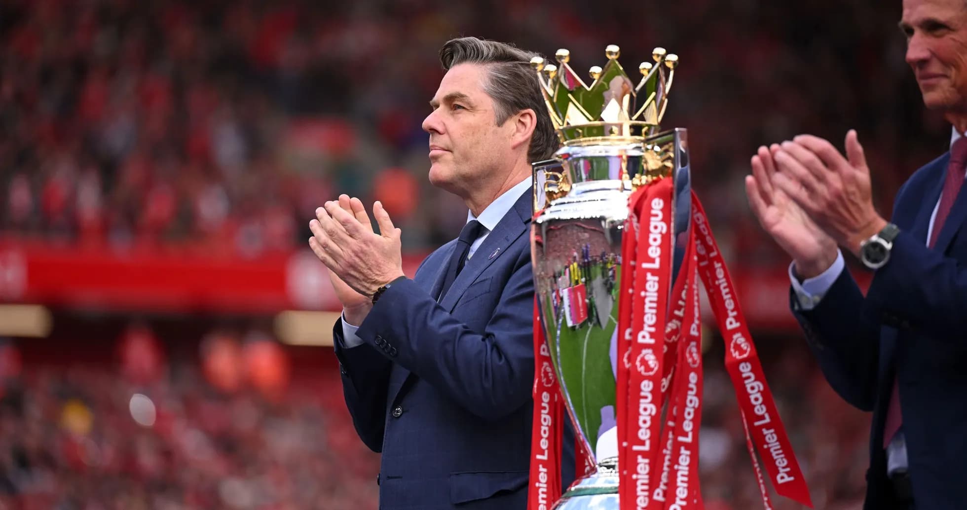 Hombre aplaudiendo junto a trofeo de la Premier League