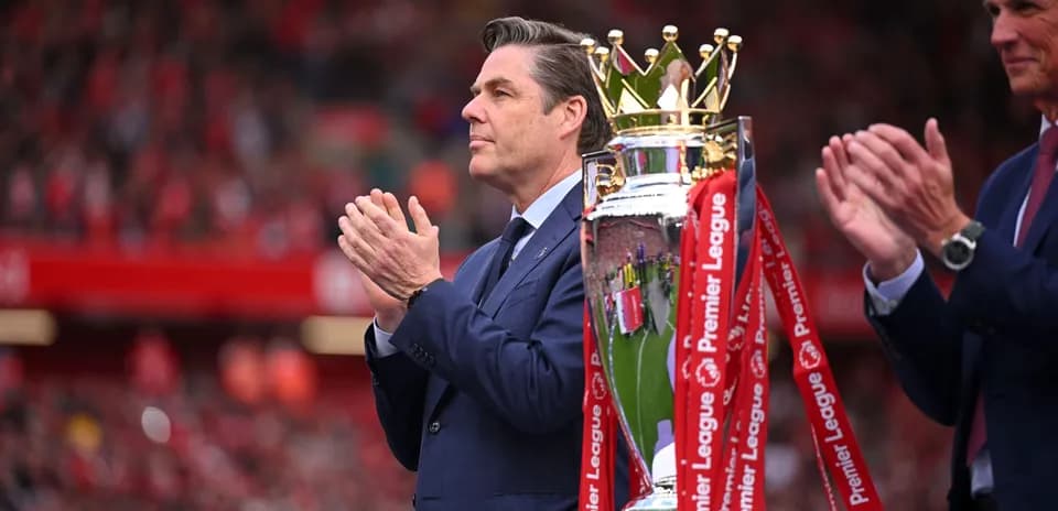 Hombre aplaudiendo junto a trofeo de la Premier League