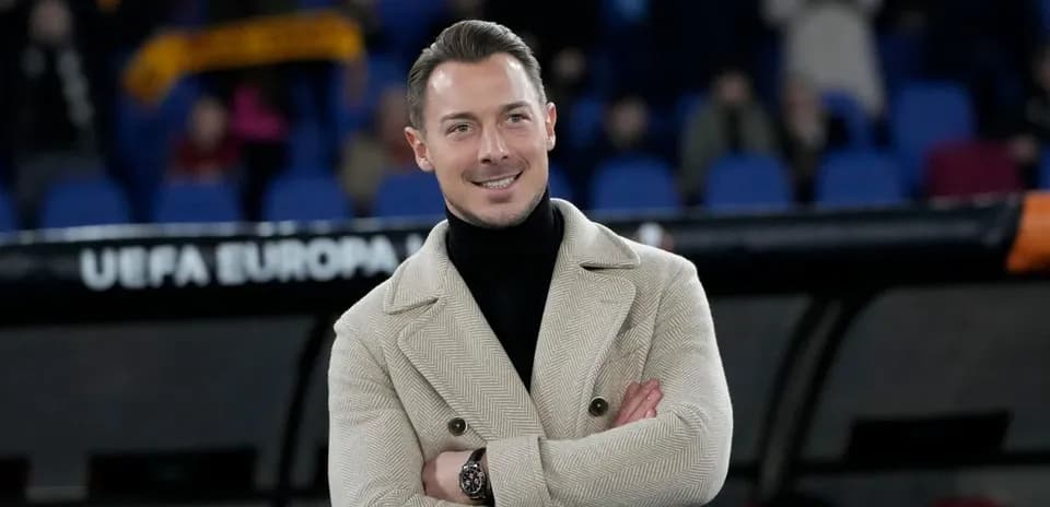 Hombre sonriente con abrigo en un estadio