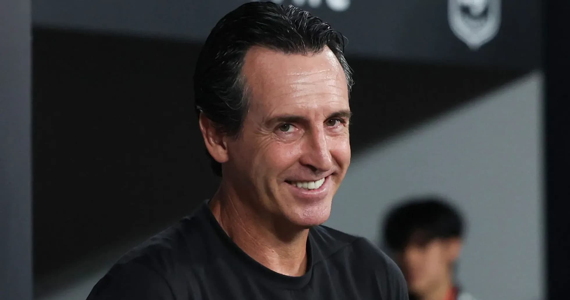 Entrenador sonriendo en la banca durante un partido