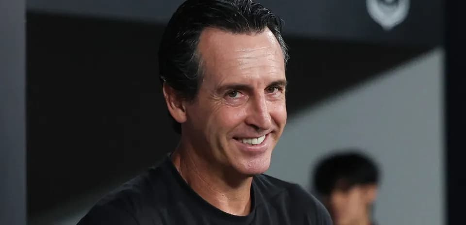Entrenador sonriendo en la banca durante un partido