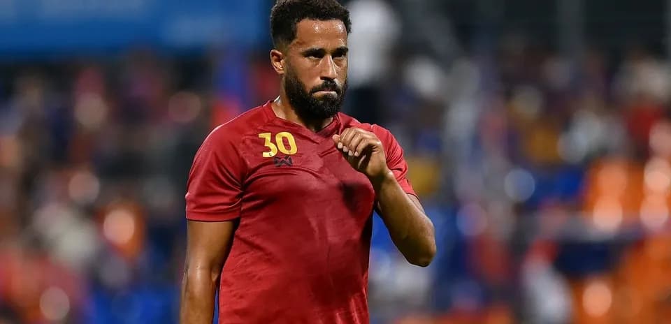 Jugador con camiseta roja caminando por el campo
