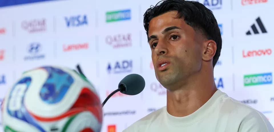 Jugador hablando en rueda de prensa con balón
