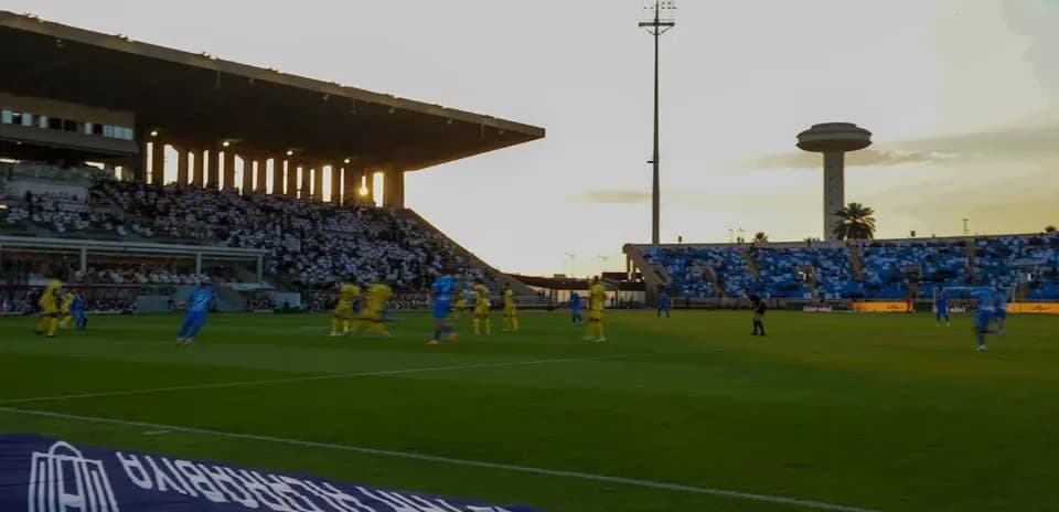 Jugadores en acción durante partido de fútbol al atardecer