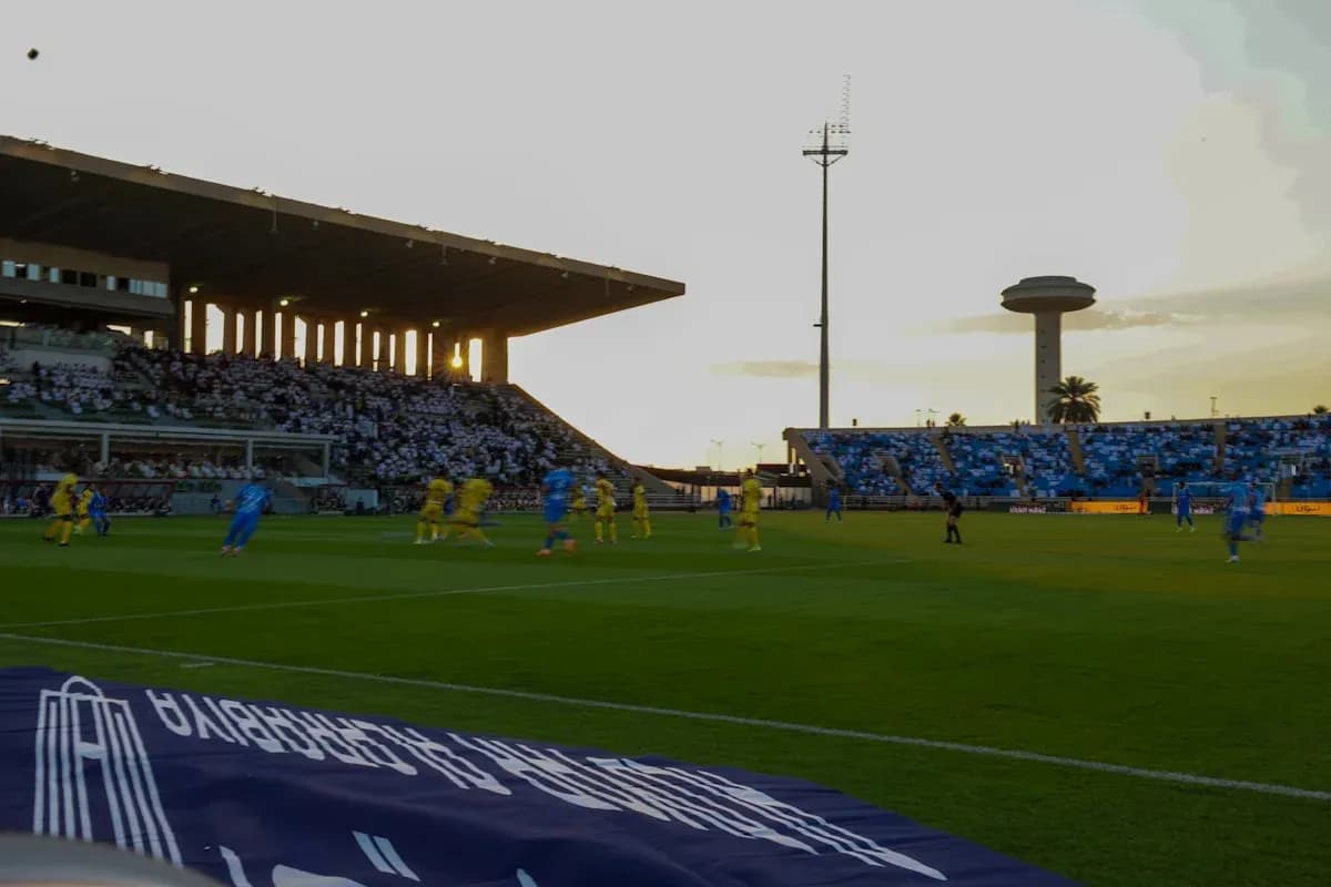 Jugadores en acción durante partido de fútbol al atardecer