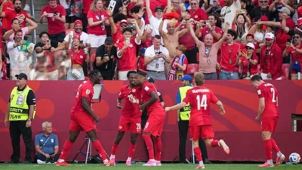 Jugadores celebrando un gol con aficionados animando