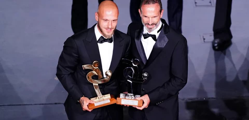 Dos hombres en trajes con premios en manos