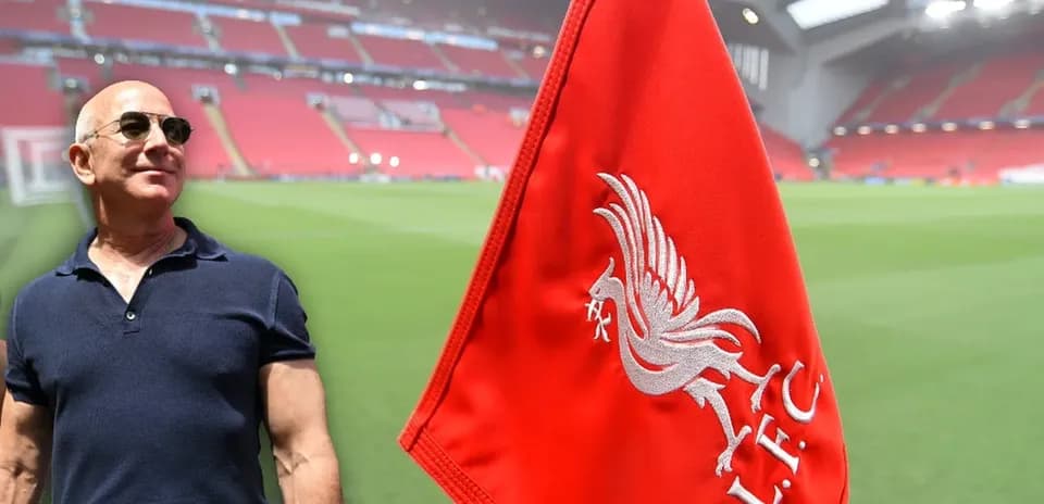 Hombre junto a bandera de Liverpool en estadio