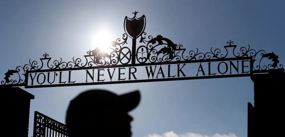 Puerta con lema 'YOU'LL NEVER WALK ALONE' iluminada por sol