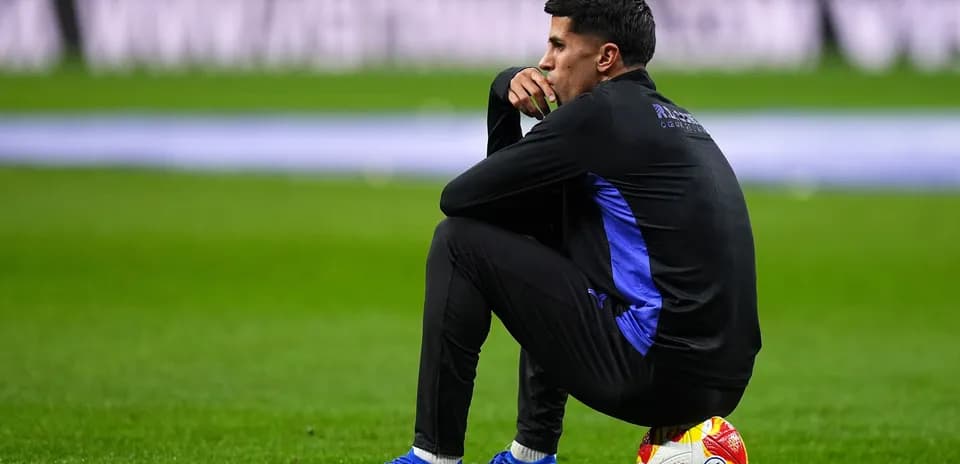 Entrenador sentado en el campo con un balón
