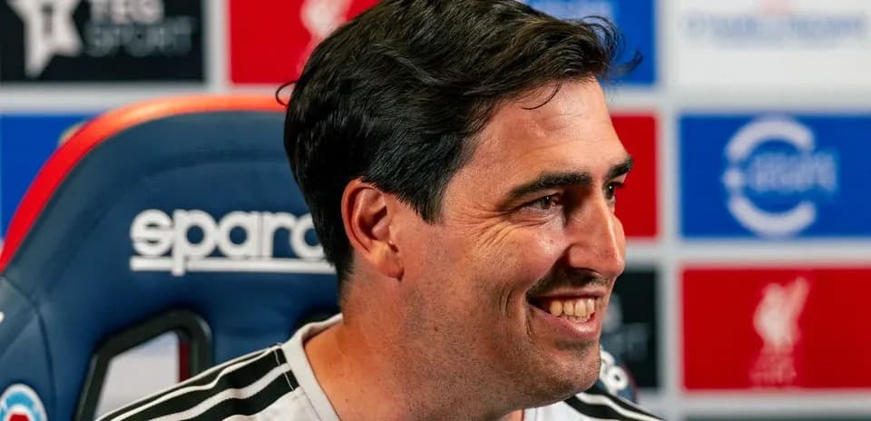 Entrenador sonriendo en rueda de prensa