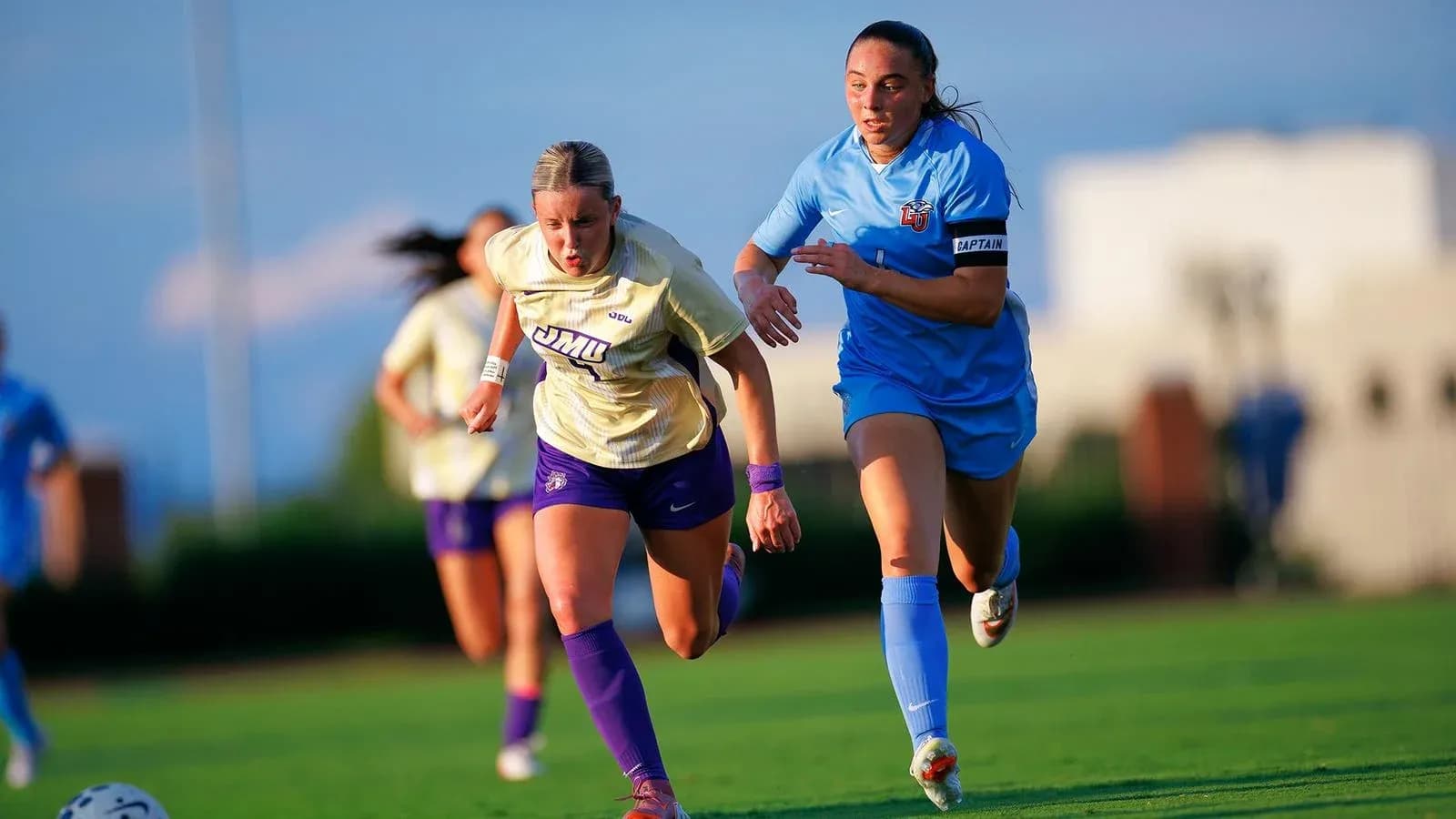 Jugadora de JMU corriendo con balón, seguida por rival