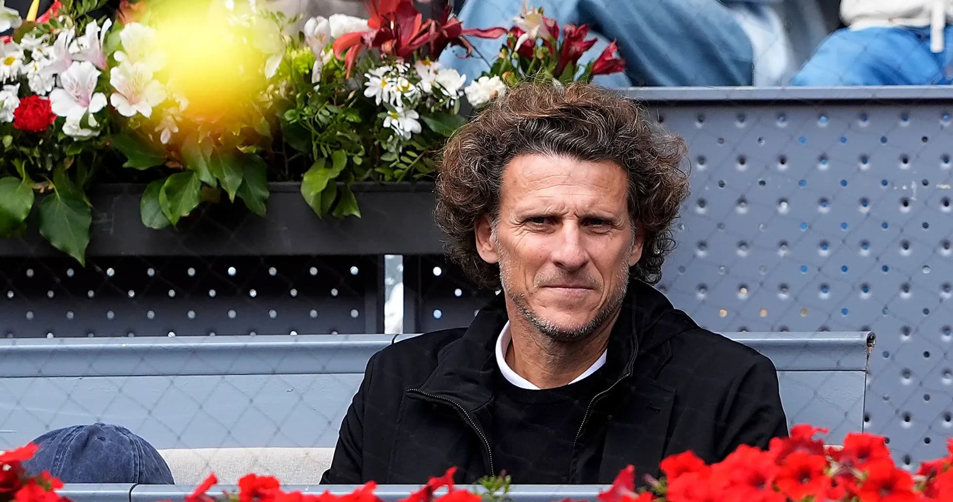 Hombre sentado en las gradas rodeado de flores
