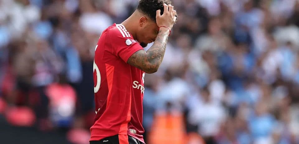Jugador con camiseta roja tocándose la cabeza en el campo