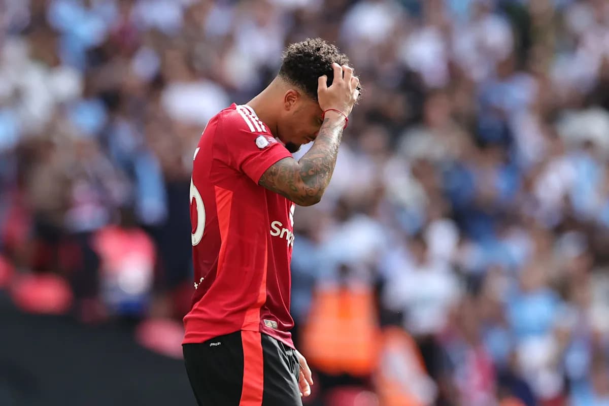 Jugador con camiseta roja tocándose la cabeza en el campo