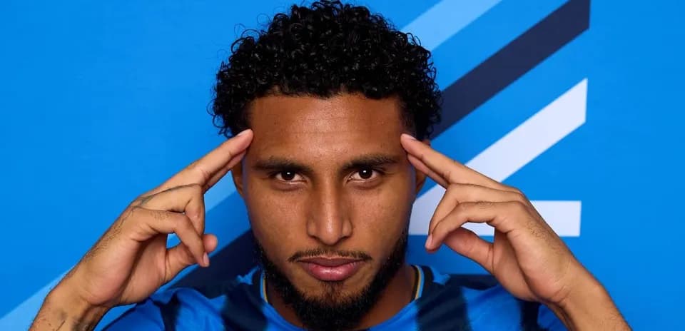 Jugador con camiseta azul posando frente a fondo azul