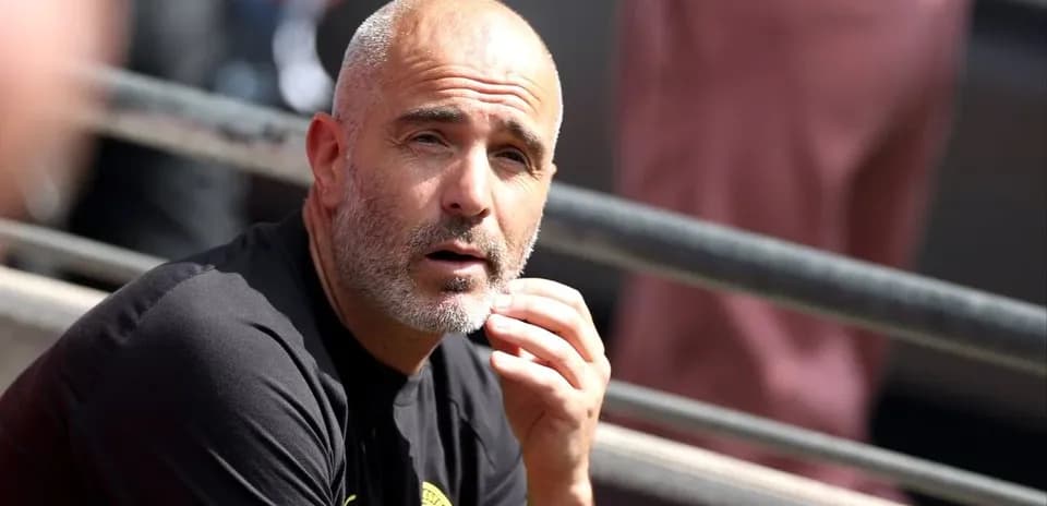 Entrenador sentado en la banca durante el partido