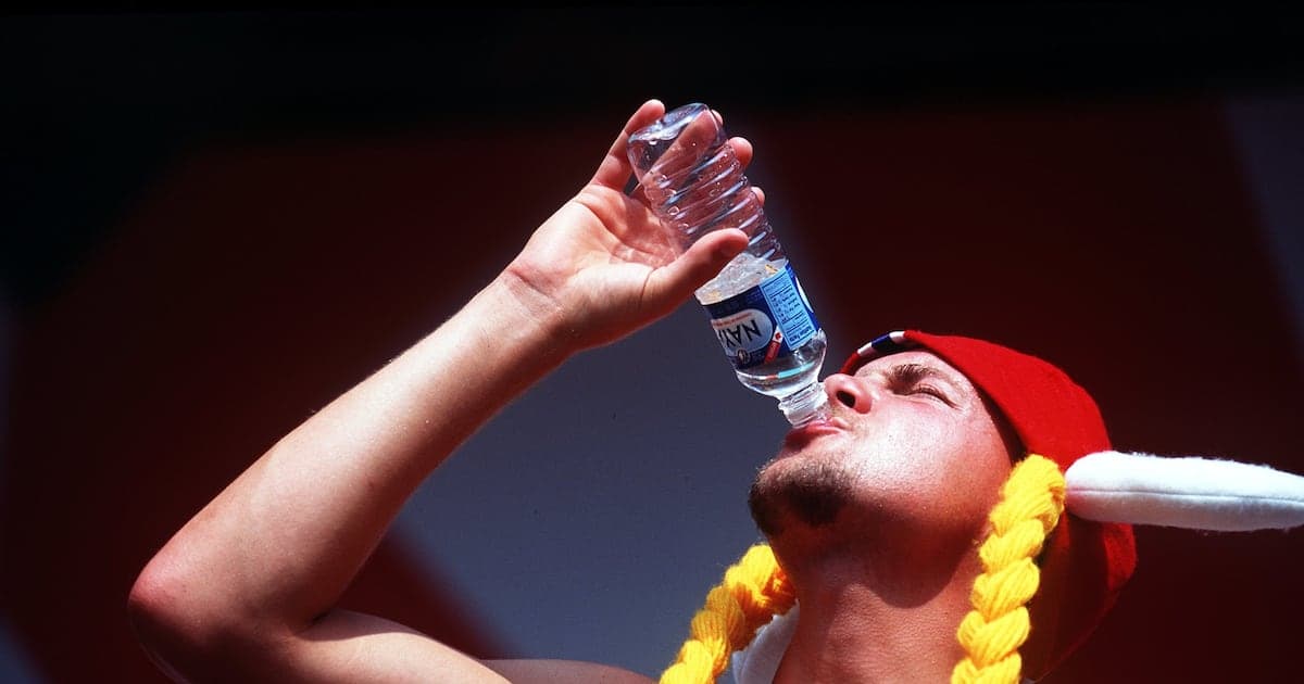 Hombre bebiendo agua de botella con gorro rojo