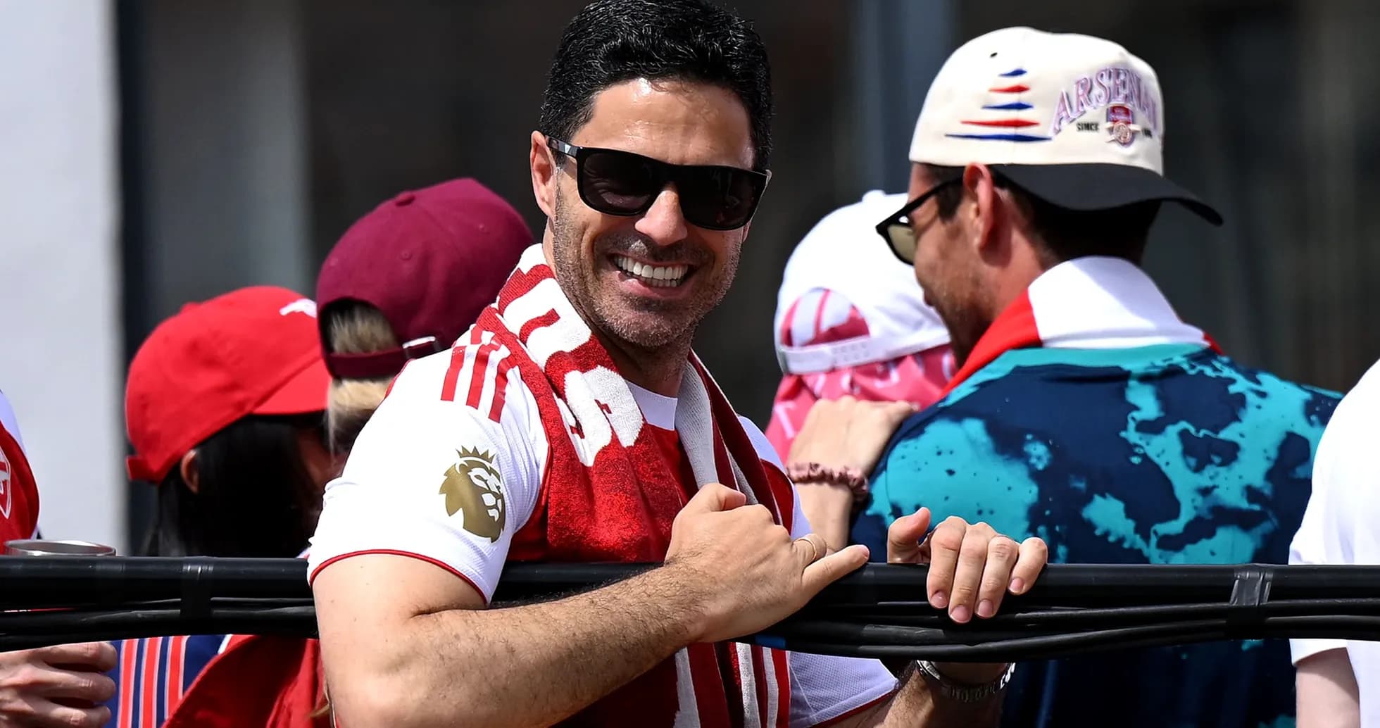 Hombre sonriendo con bufanda de Arsenal en evento