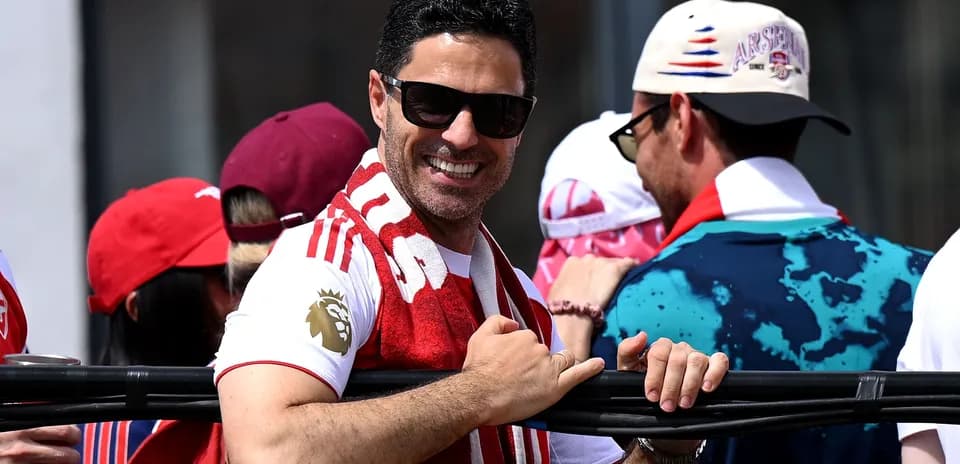 Hombre sonriendo con bufanda de Arsenal en evento
