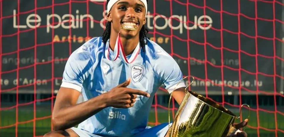 Jugador sosteniendo trofeo frente a la portería