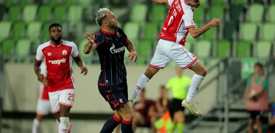 Jugador de FK Crvena Zvezda saltando por el balón