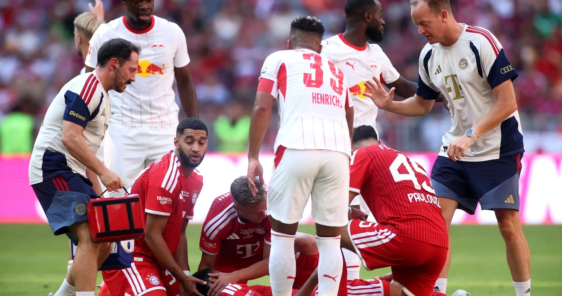 Jugadores de Bayern y Leipzig en el campo atendiendo a un jugador