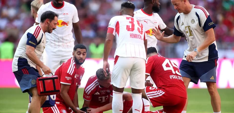 Jugadores de Bayern y Leipzig en el campo atendiendo a un jugador
