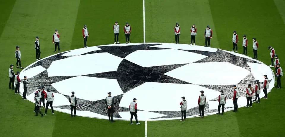 Personal colocando el logo de la Champions League en el campo