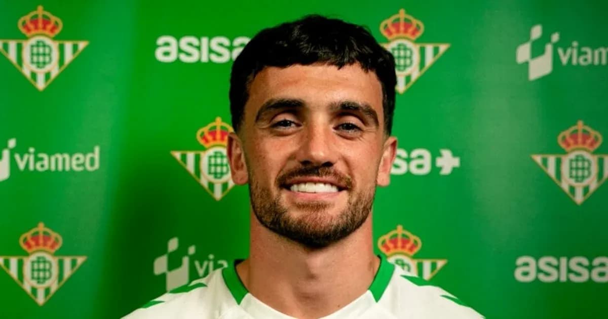 Jugador sonriendo frente a fondo del Real Betis