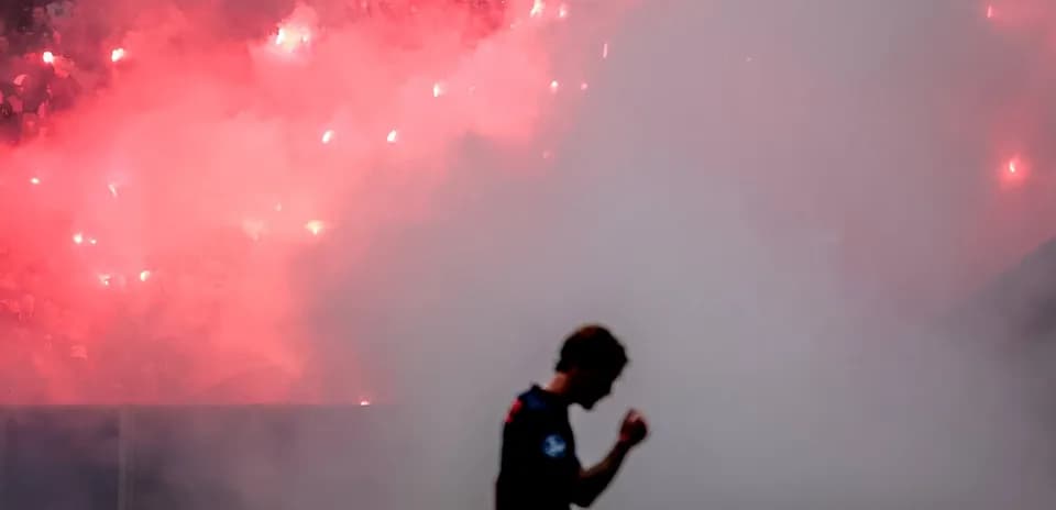 Jugador celebrando con humo y bengalas de fondo