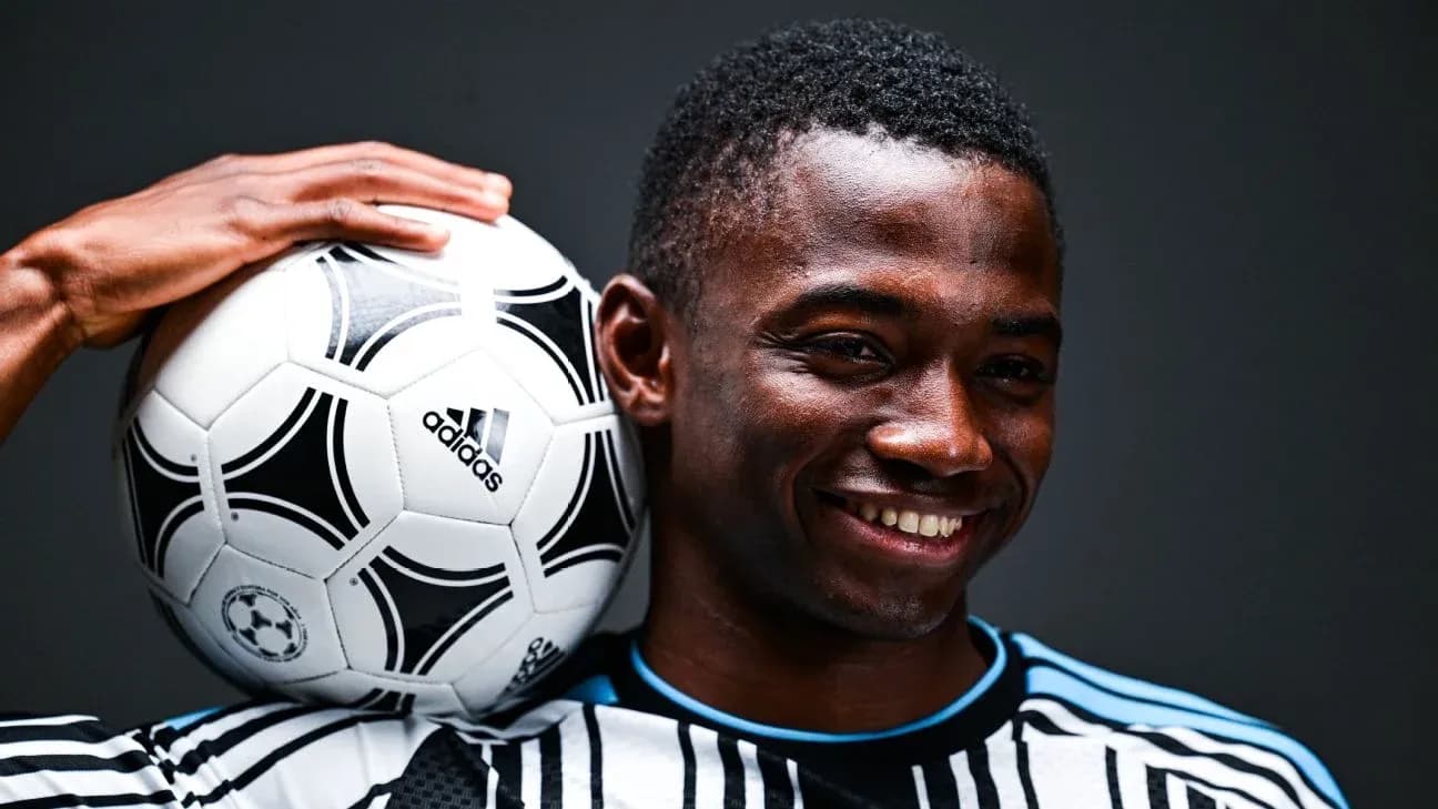 Jugador sosteniendo un balón de fútbol sobre su hombro