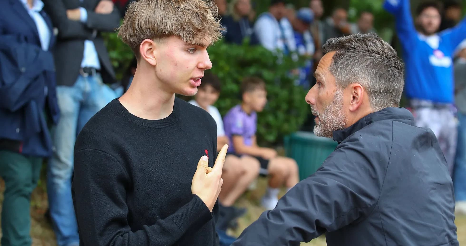 Joven discutiendo con un hombre mayor en evento deportivo