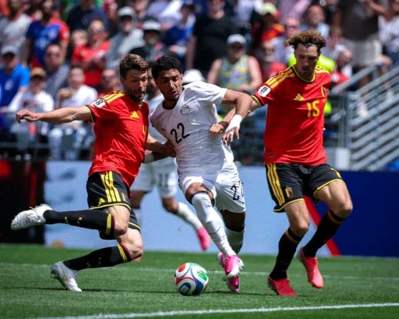 Jugador de Egipto esquivando a dos rivales belgas Jugador de Egipto esquivando a dos rivales belgas