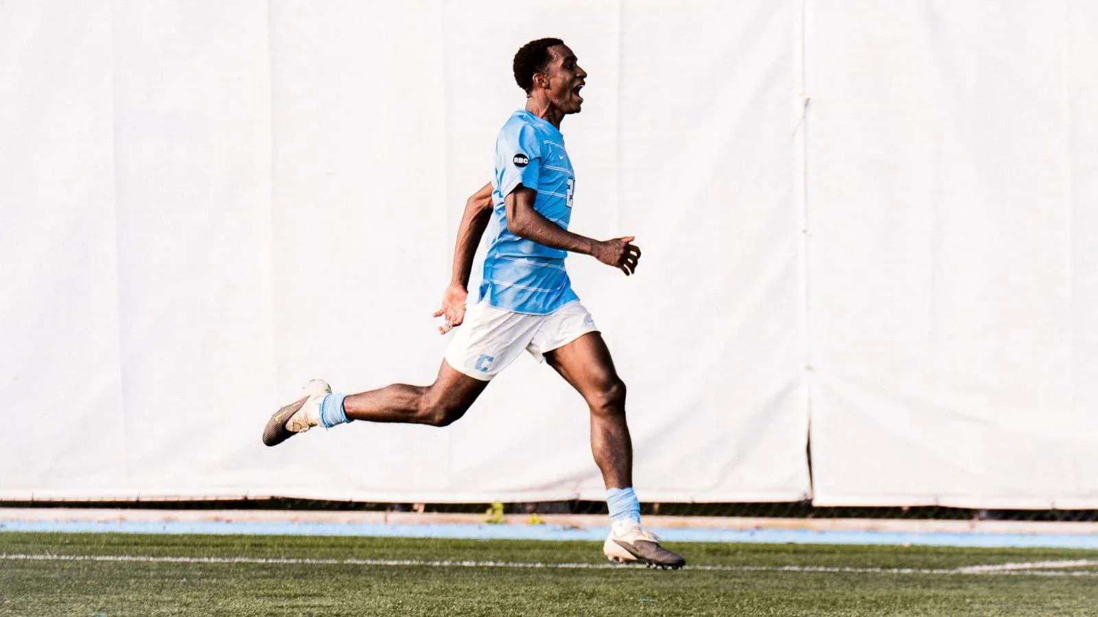 Jugador corriendo en el campo con camiseta azul Jugador corriendo en el campo con camiseta azul