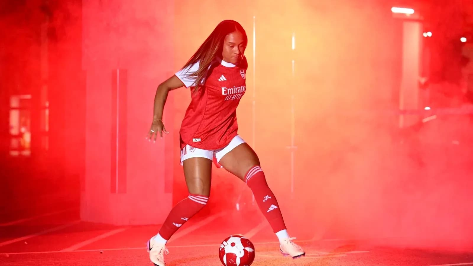 Jugadora de fútbol en uniforme de Arsenal con balón Jugadora de fútbol en uniforme de Arsenal con balón