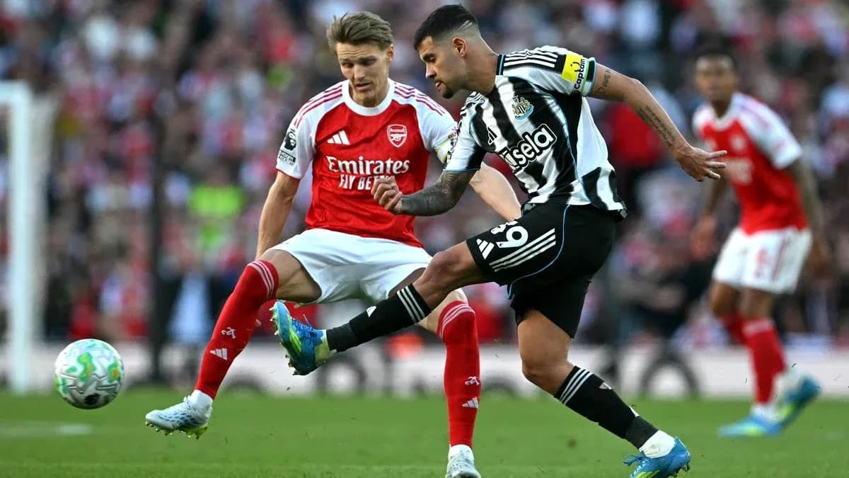Jugador de Newcastle chutando el balón ante rival de Arsenal Jugador de Newcastle chutando el balón ante rival de Arsenal