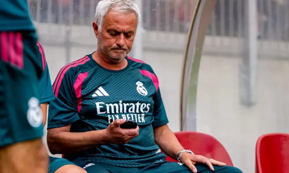 Entrenador de Real Madrid revisando su teléfono en banco Entrenador de Real Madrid revisando su teléfono en banco