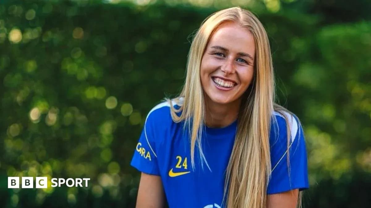 Jugadora de fútbol sonriendo en camiseta azul Jugadora de fútbol sonriendo en camiseta azul
