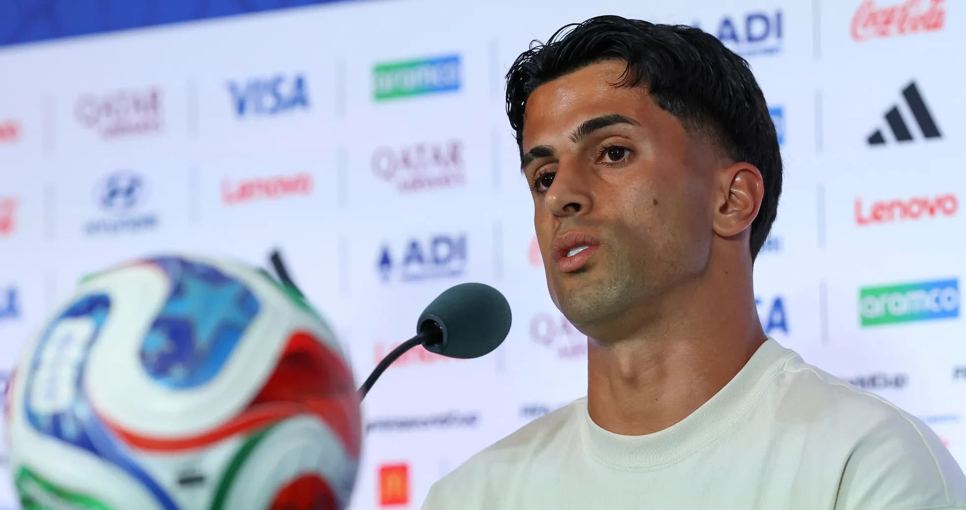 Jugador hablando en rueda de prensa con balón Jugador hablando en rueda de prensa con balón