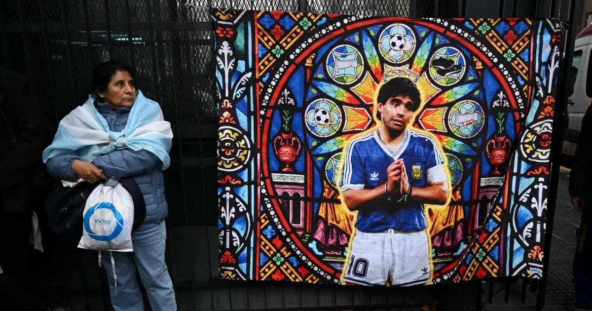 Mujer con bandera argentina junto a mural de Maradona Mujer con bandera argentina junto a mural de Maradona