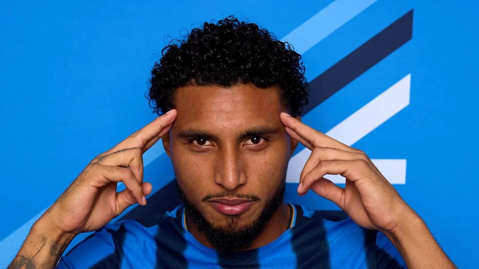 Jugador con camiseta azul posando frente a fondo azul Jugador con camiseta azul posando frente a fondo azul