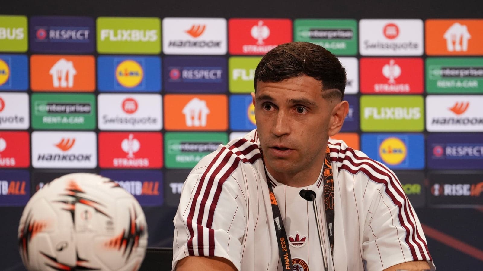 Jugador en conferencia de prensa con balón frente a él Jugador en conferencia de prensa con balón frente a él