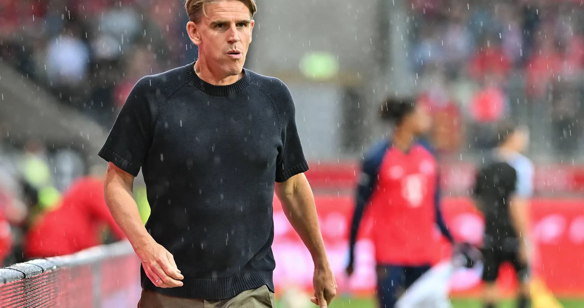 Entrenador caminando en la lluvia durante el partido Entrenador caminando en la lluvia durante el partido